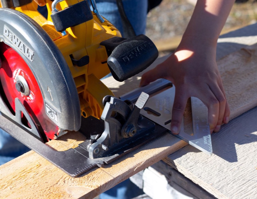 Carpenter measuring a deck board on a Saginaw job site